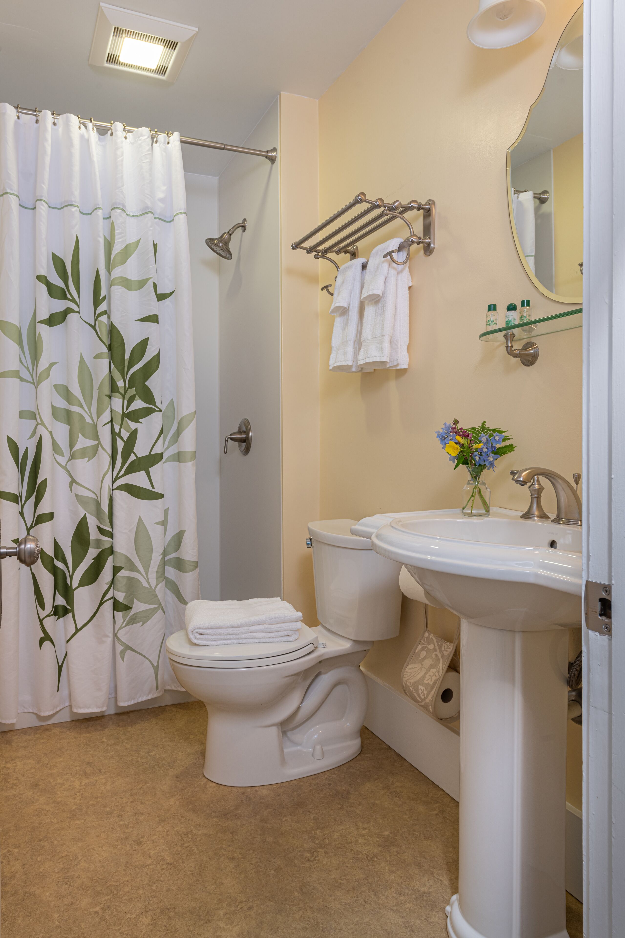 A bathroom with a toilet, sink, shower, and towel rack.