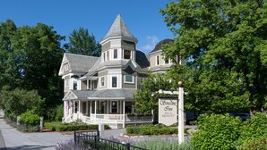 A large, historic house with a prominent tower and a sign for the Simplicity Inn, indicating it offers bed and breakfast services.