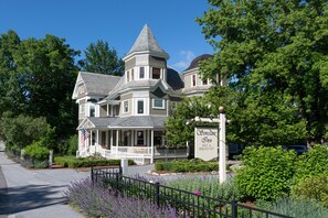 A large, historic house with a prominent tower and a sign for the Simplicity Inn, indicating it offers bed and breakfast services.