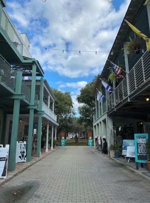 A street with buildings on either side, a clear sky, and some flags. - Cozy studio in the heart of Seaside walking distance to the beach (Santa Rosa Beach)