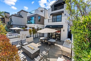 A modern outdoor patio area with seating, a fire feature, and a grill. - Gorgeous home for Executive re-location, Digital Nomads, or Families (Huntington Beach)