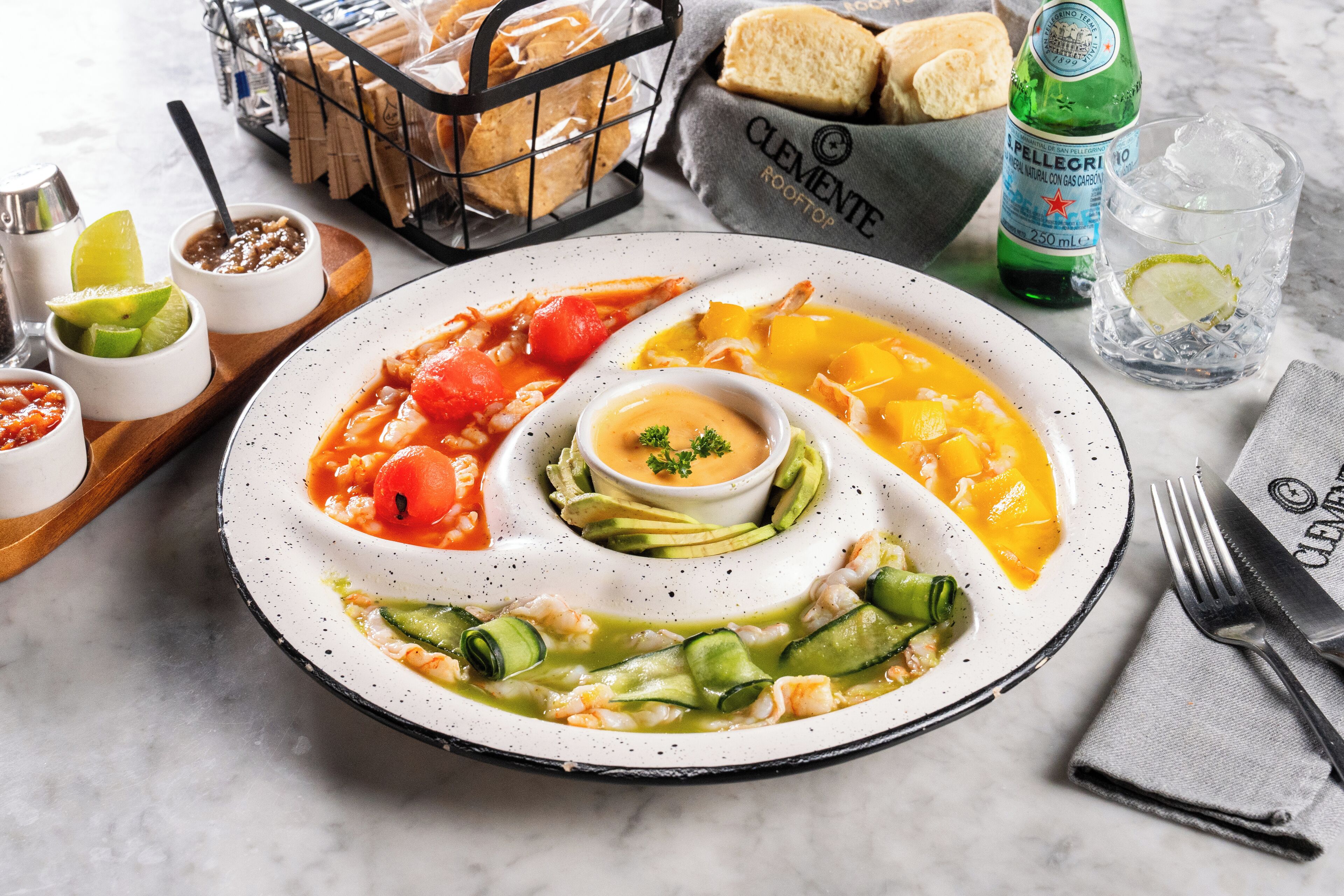 Un plato de comida con varios guisos, una botella de agua y un vaso de agua.