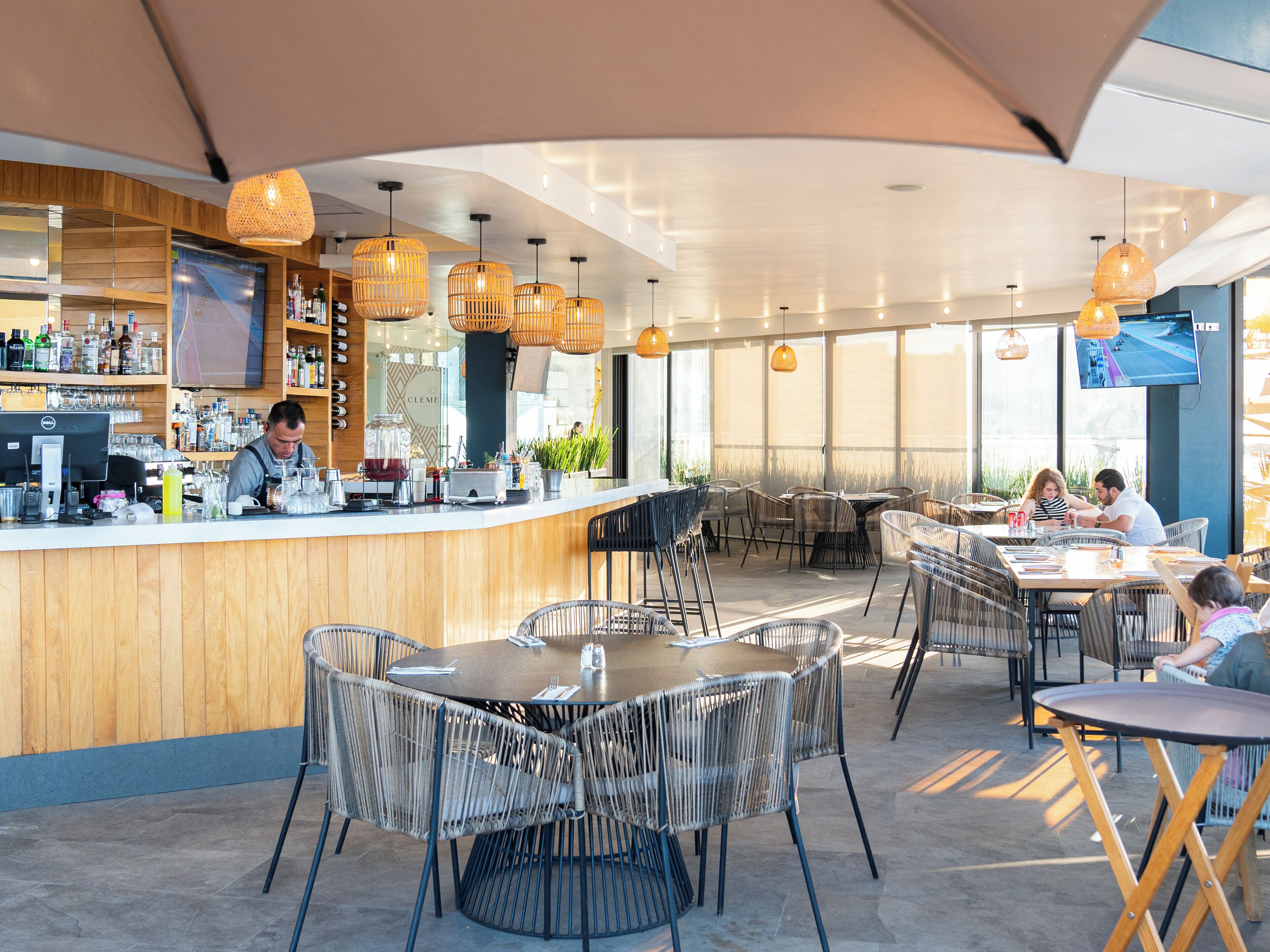 Ein modernes Restaurant mit Holztresen, Korbstühlen und Pendelleuchten.