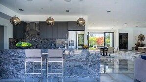 A modern kitchen with marble countertops, stainless steel appliances, and pendant lighting. - Troy Dr - Sleek & Modern Hollywood Hills Home With Stunning Views (Los Angeles)
