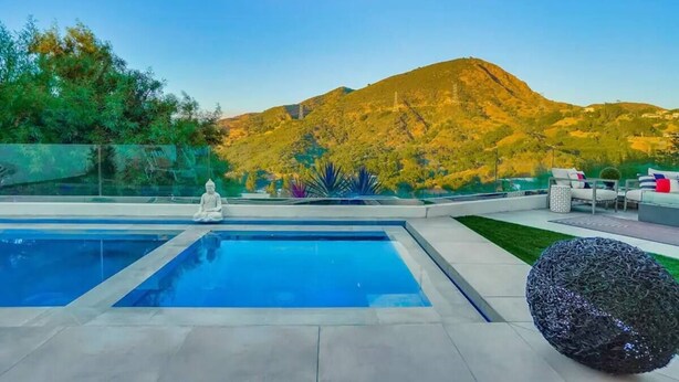 A modern outdoor pool area with a Buddha statue, a decorative spherical sculpture, and a view of a mountain. - Troy Dr - Sleek & Modern Hollywood Hills Home With Stunning Views (Los Angeles)