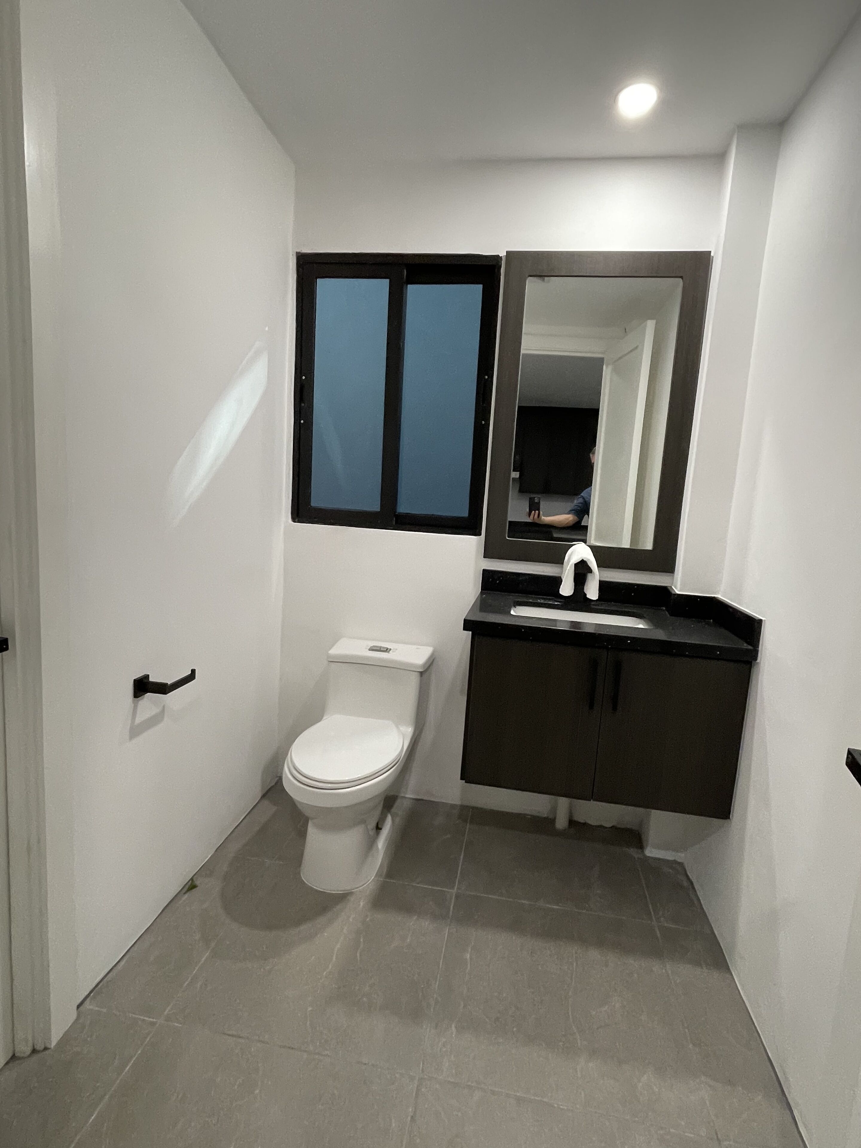 Een badkamer met toilet, wastafel en spiegel.