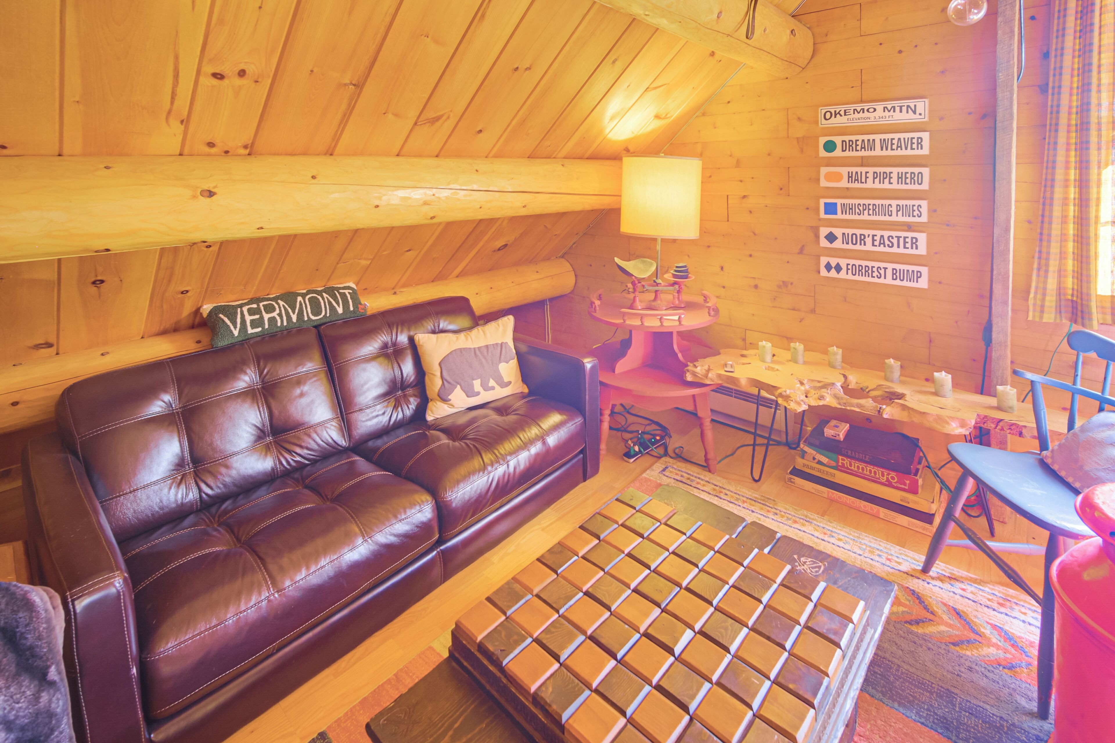 L’intérieur chaleureux d ’un chalet en bois comprend un canapé en cuir, une petite table et un panneau indiquant les attractions situées à proximité.