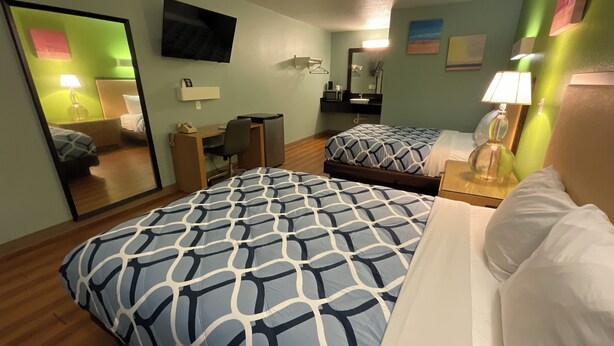 Une chambre d’hôtel avec deux lits, un bureau, une chaise, une télévision et un miroir.