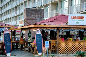 Ein Strandrestaurant namens 'Coconuts' mit Außenbereich und einem Schild, das 'Home of the Naked Turtle' anzeigt.