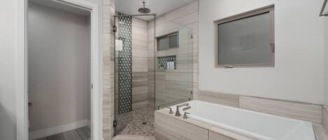 A modern bathroom with a walk-in shower, a large bathtub, and a glass-enclosed shower area.