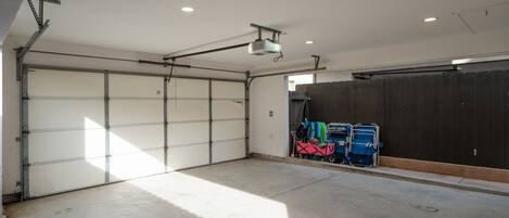A garage with a concrete floor, a closed garage door, and a wooden fence.