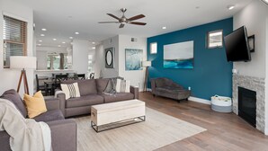 A modern living room with a grey sofa, a wooden coffee table, and a fireplace. - Large Family Beach Home | 1 Block to Beach & More | AC (San Diego)