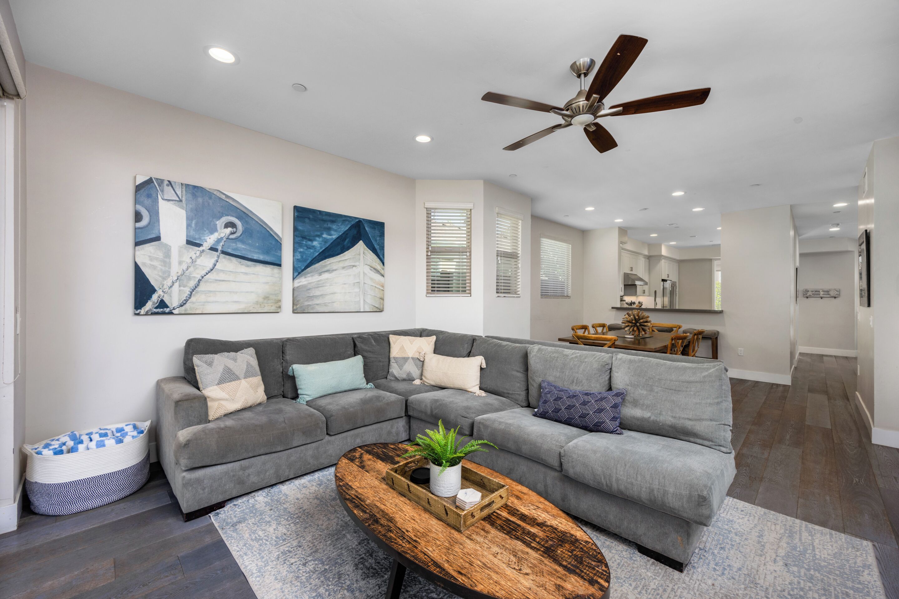 A modern living room with a gray sectional sofa, a wooden coffee table, and a ceiling fan.