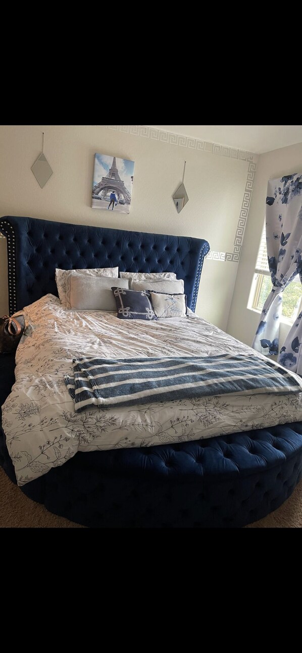 Cozy retreat with a tufted headboard, floral-patterned duvet, and a framed Eiffel Tower print.
