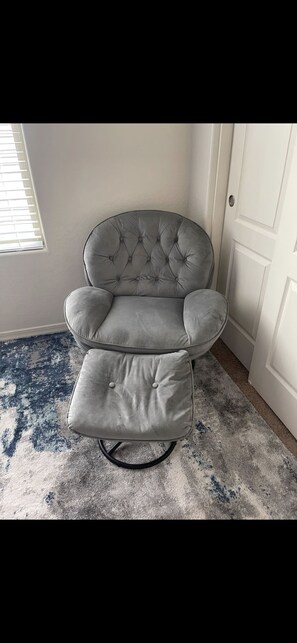 Relax in a cozy corner with a tufted armchair and plush carpet.