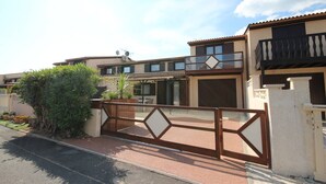 A residential building with a gated entrance, a balcony, and a clear sky. - Pleasant renovated fenced house with air conditioning, Wifi, DOMAINE TAMARIS, 3 bedrooms, sleeps... (PORTIRAGNES)