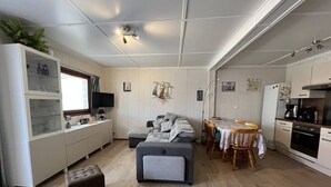 A compact living space with a kitchenette, a dining area, and a seating area with a sofa and ottoman. - Pleasant renovated fenced house with air conditioning, Wifi, DOMAINE TAMARIS, 3 bedrooms, sleeps... (PORTIRAGNES)