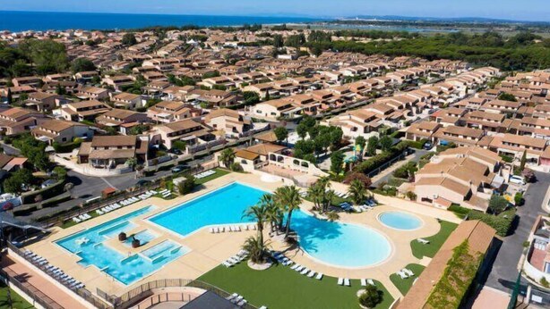 A resort with multiple bungalow-style accommodations, a central swimming pool, and a view of the sea. - Pleasant renovated fenced house with air conditioning, Wifi, DOMAINE TAMARIS, 3 bedrooms, sleeps... (PORTIRAGNES)