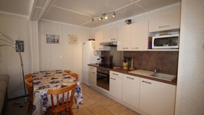 A compact kitchen with white cabinets, a microwave, a coffee maker, and a dining table with chairs. - Pleasant renovated fenced house with air conditioning, Wifi, DOMAINE TAMARIS, 3 bedrooms, sleeps... (PORTIRAGNES)