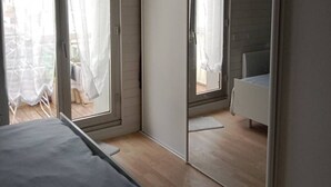 Ett sovrum med en säng, ett litet sängbord och ett fönster med gardiner.