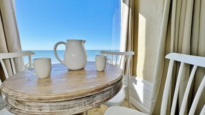 A wooden table with a pitcher and two mugs on a balcony overlooking the sea. - Cozy Beachfront Retreat right on the Sand, Sparkling Pool, & Charming Coastal Flair! (Belleair Beach)