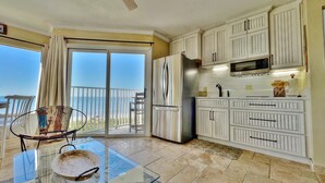 A kitchen with white cabinets, a stainless steel refrigerator, and a microwave. - Cozy Beachfront Retreat right on the Sand, Sparkling Pool, & Charming Coastal Flair! (Belleair Beach)