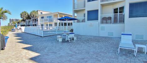 A hotel courtyard with outdoor seating, a pool, and a white fence.