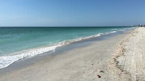 A beach with a wide sandy shore and gentle waves. - Cozy Beachfront Retreat right on the Sand, Sparkling Pool, & Charming Coastal Flair! (Belleair Beach)