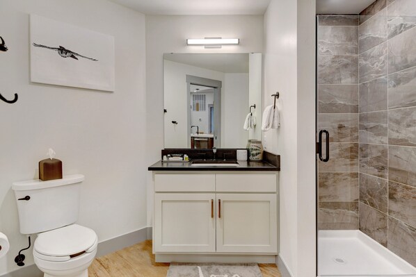 A modern bathroom with a toilet, sink, and shower.