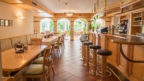 A restaurant with a long counter, bar stools, and a bar area with a coffee machine.