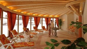 A spa area with wooden beams, large windows with orange curtains, and lounge chairs.