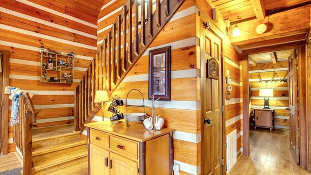 Ein Holzhäuschen im Inneren mit Treppe, Holzwänden, einer Küchenzeile inklusive Spüle und einem Regal mit diversen Gegenständen.
