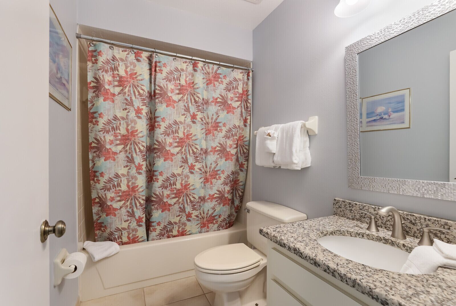 Une salle de bain équipée d’un rideau de douche, de toilettes, d’un lavabo et d’un miroir.
