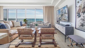 A modern living room with a large TV, comfortable seating, and a view of the ocean. - Awesome 3 bedroom condo Encantame Tower E 301 (Puerto Peñasco)