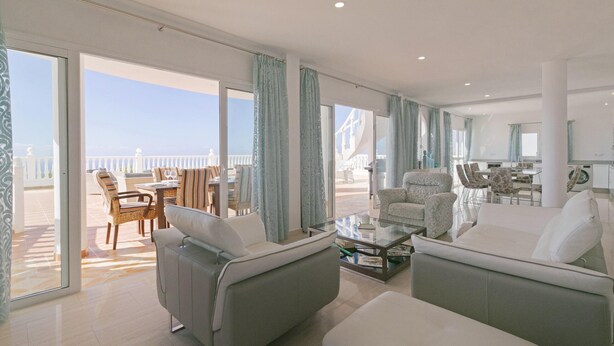 A spacious living area with a balcony, furnished with sofas and a dining table. - Villa Panoramica (Costa Adeje)