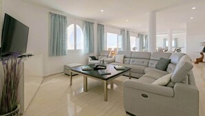 A modern living room with a sectional sofa, a glass coffee table, and a flat-screen TV. - Villa Panoramica (Costa Adeje)