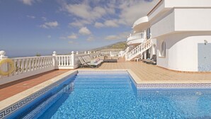A swimming pool with a white balustrade, lounge chairs, and a tiled deck. - Villa Panoramica (Costa Adeje)
