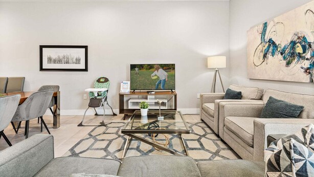 Un soggiorno con zona pranzo, televisore, divano e un quadro appeso al muro.