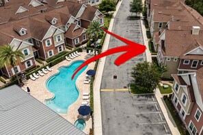 A residential area with a swimming pool surrounded by lounge chairs and umbrellas. - 4BR Summerville Resort Villa in Kissimmee | Near Disney, Pool, Safety (Kissimmee)