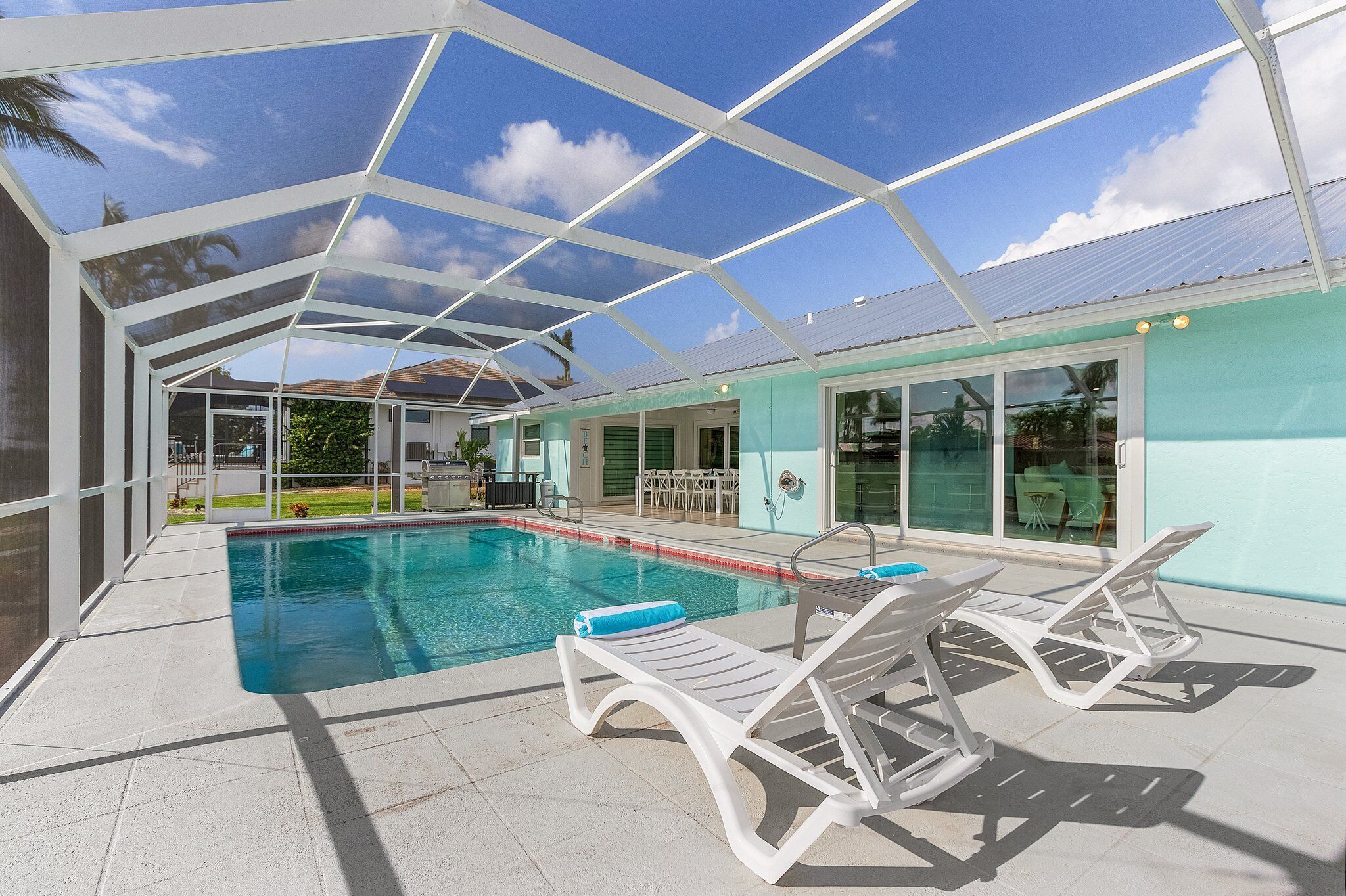 Una piscina esterna coperta con sdraio e una porta in vetro che dà su un patio.