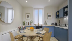 Une cuisine moderne avec une table de salle à manger ronde, des chaises en bois et un saladier rempli de fruits.