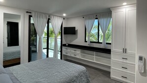 Un dormitorio con cama, televisor, armario y balcón.
