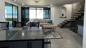 Un interior moderno con zona de comedor, sofá y escalera.