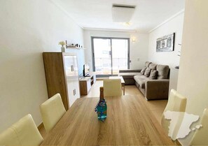 Un salon moderne comprenant un canapé, une table à manger avec des chaises, un meuble et une grande fenêtre.