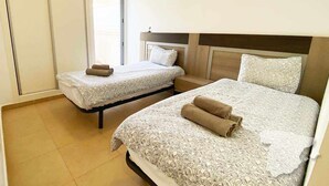 Een hotelkamer met twee bedden, een groot raam en een kledingkast.