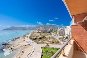 A coastal cityscape with a beach, buildings, and a mountain in the background.