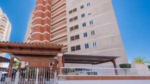 Un edificio residenziale a più piani con un ingresso carrabile e una zona esterna coperta.