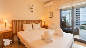 A hotel room with a large bed, two bedside tables, a window with a view of buildings, and a balcony with chairs. - CostaBlancaDreams - Morello 5a in Calpe (Calpe)