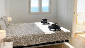 A bedroom with a bed, a window with a view of the sea, and a bathroom with a towel rack. - CostaBlancaDreams - Duplex Cap Negret in Altea (Altea)
