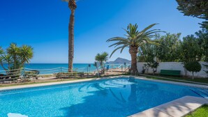 A swimming pool with clear blue water, surrounded by palm trees and a white wall. - CostaBlancaDreams - Duplex Cap Negret in Altea (Altea)